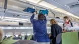 Three people, one placing bags into overhead bin